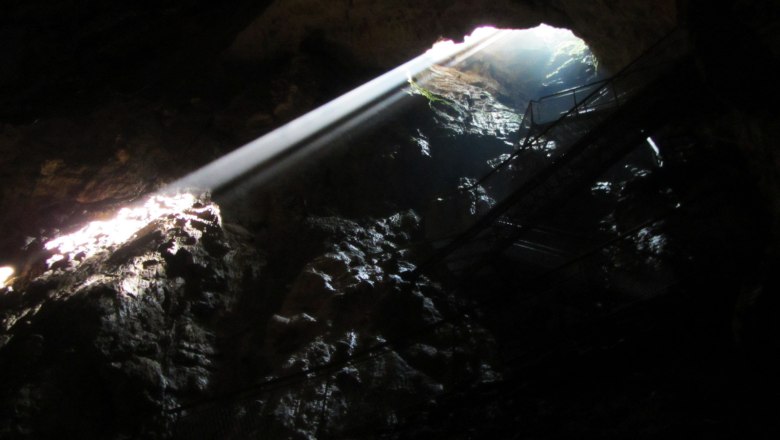 Sonnenstrahlen in der Tropfsteinhöhle, © Mostviertel Tourismus, Karas Sonnenstrahlen dringen durch eine Öffnung in einer dunklen Tropfsteinhöhle.