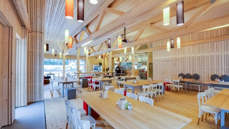 Ötscher-Basis Wienerbruck, © Fred Lindmoser Innenansicht eines modernen Restaurants mit Holzmöbeln und bunten Hängelampen.