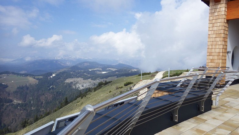 Ausblick vom Terzerhaus, © Abl Aussicht vom Terzerhaus auf eine bergige Landschaft mit Wolken und einem Geländer im Vordergrund.