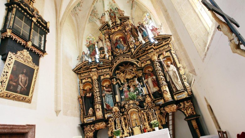Innenansicht der Wallfahrtskirche Annaberg mit reich verziertem Altar und religiösen Statuen.