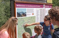 Familien genießen einen spannenden Moment, während sie die Wanderkarte studieren und sich auf das Abenteuer in der atemberaubenden Natur vorbereiten. Umgeben von üppigem Grün und majestätischen Bergen, verspricht dieser Ort unvergessliche Erlebnisse für Groß und Klein.