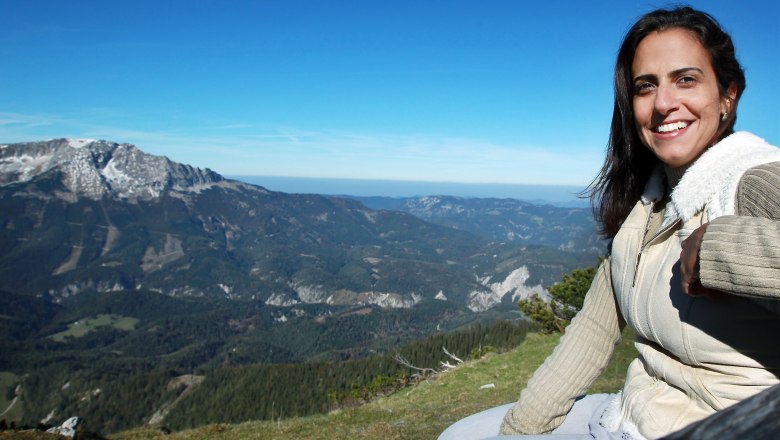 Woman sitting on a mountain with a view of a mountain landscape.