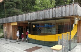 Bahnhof Erlaufklause mit Holzfassade und Glasfront, Menschen betreten das Gebäude.