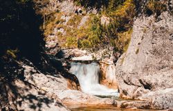Ein sanft plätschernder Wasserfall umrahmt von majestätischen Felsen und üppigem Grün lädt zu einer erfrischenden Auszeit in der Natur ein. Die klare Luft und das beruhigende Geräusch des Wassers schaffen eine harmonische Atmosphäre, die Wanderer und Naturliebhaber gleichermaßen begeistert.
