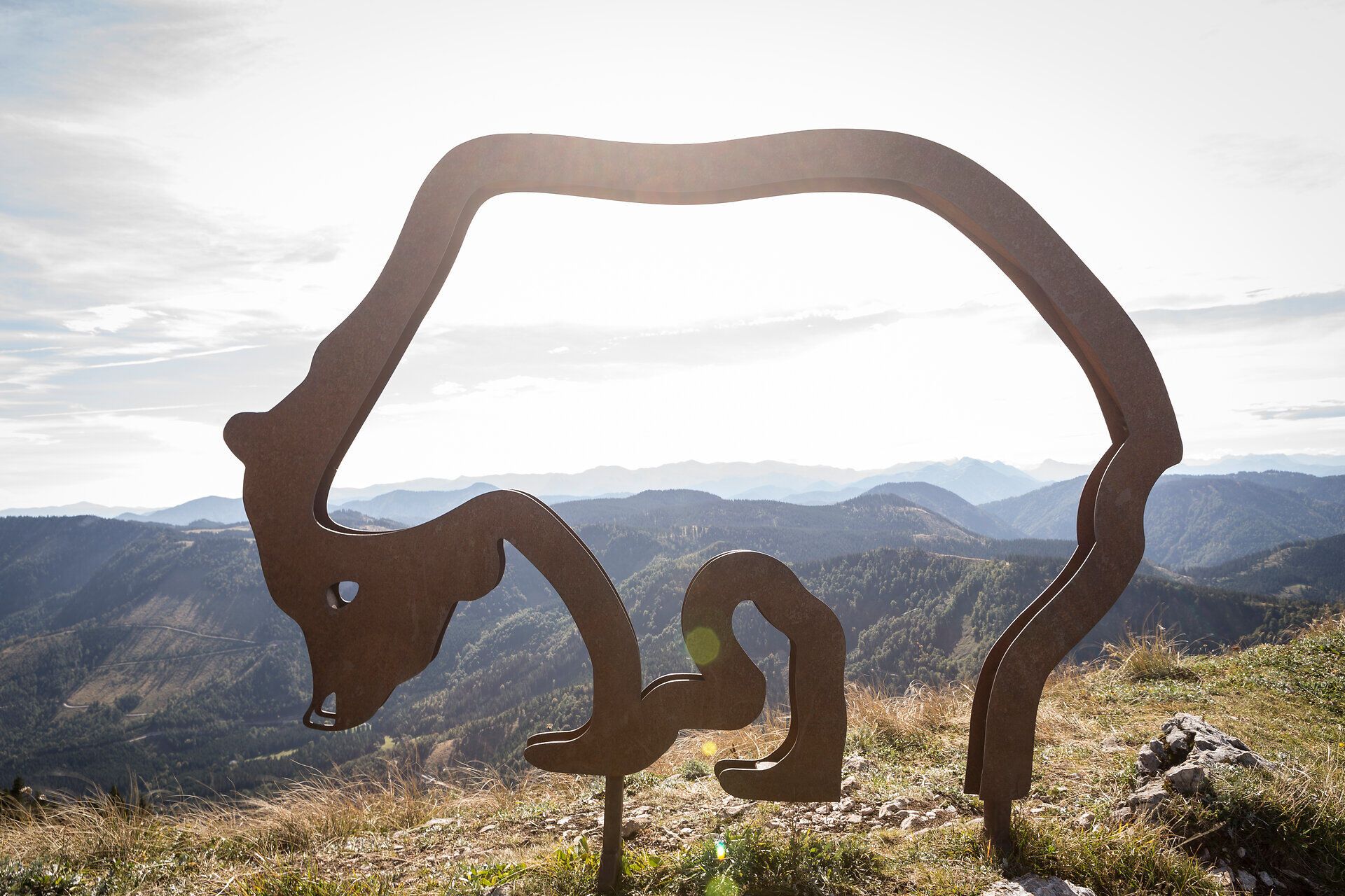 Ein majestätisches Bären-Symbol erhebt sich vor der beeindruckenden Berglandschaft, die den Wanderern unvergessliche Ausblicke bietet. Die sanften Hügel und die klare Luft laden dazu ein, die Natur in vollen Zügen zu genießen und die Seele baumeln zu lassen.