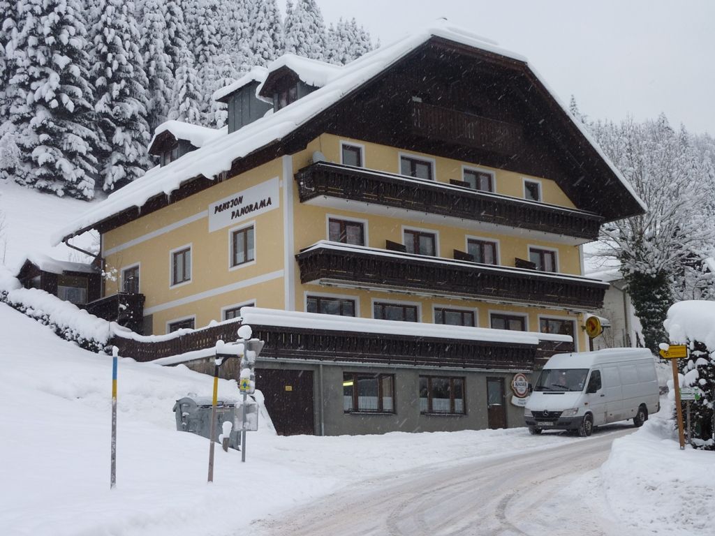 A snow-covered building with the inscription 'Pension Panorama' in a wintry landscape.