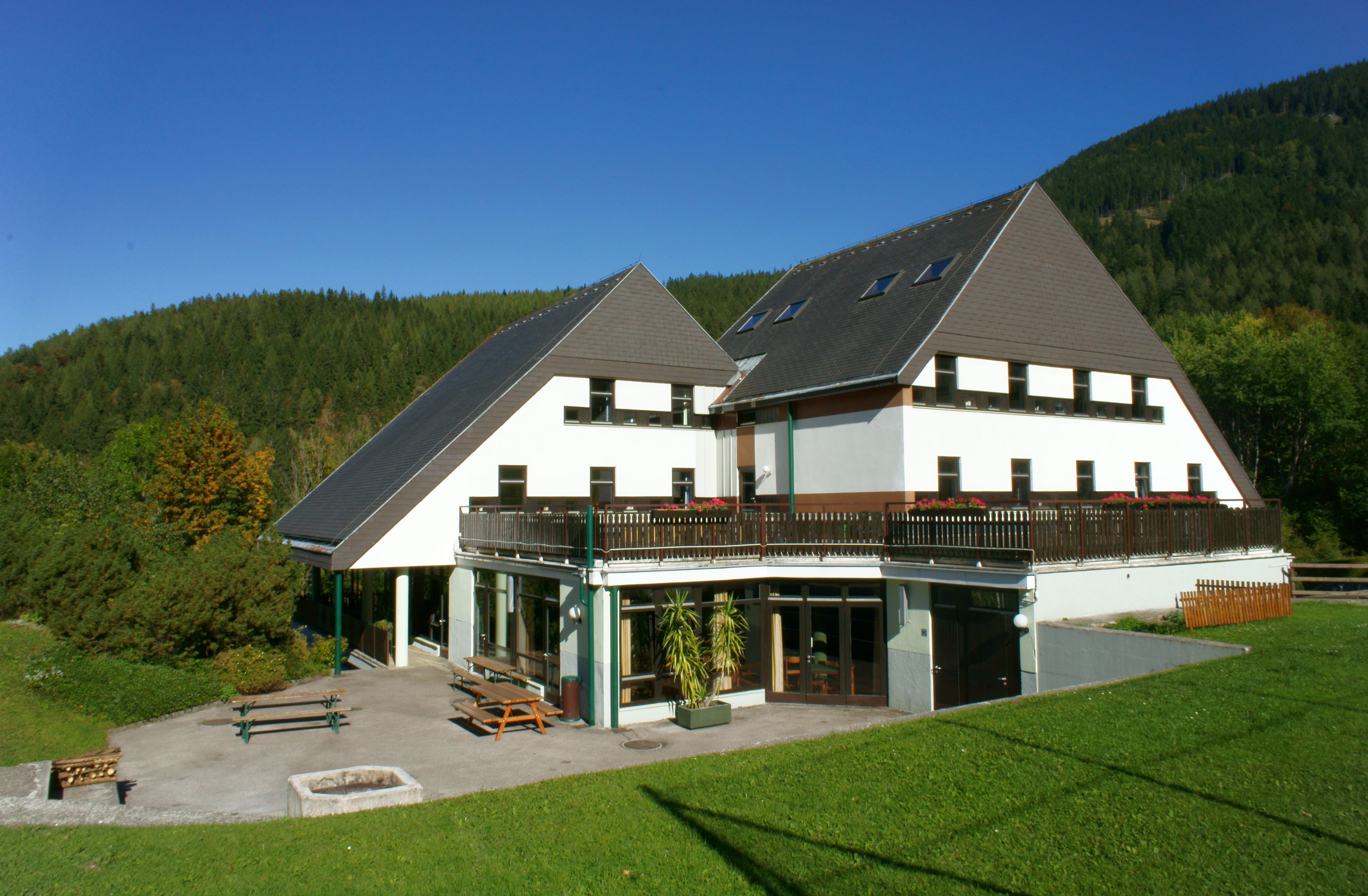 Ein modernes Gebäude mit spitzem Dach in einer grünen Landschaft.