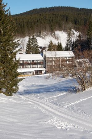 Verschneites Hotel in einer Berglandschaft mit Tannenbäumen.