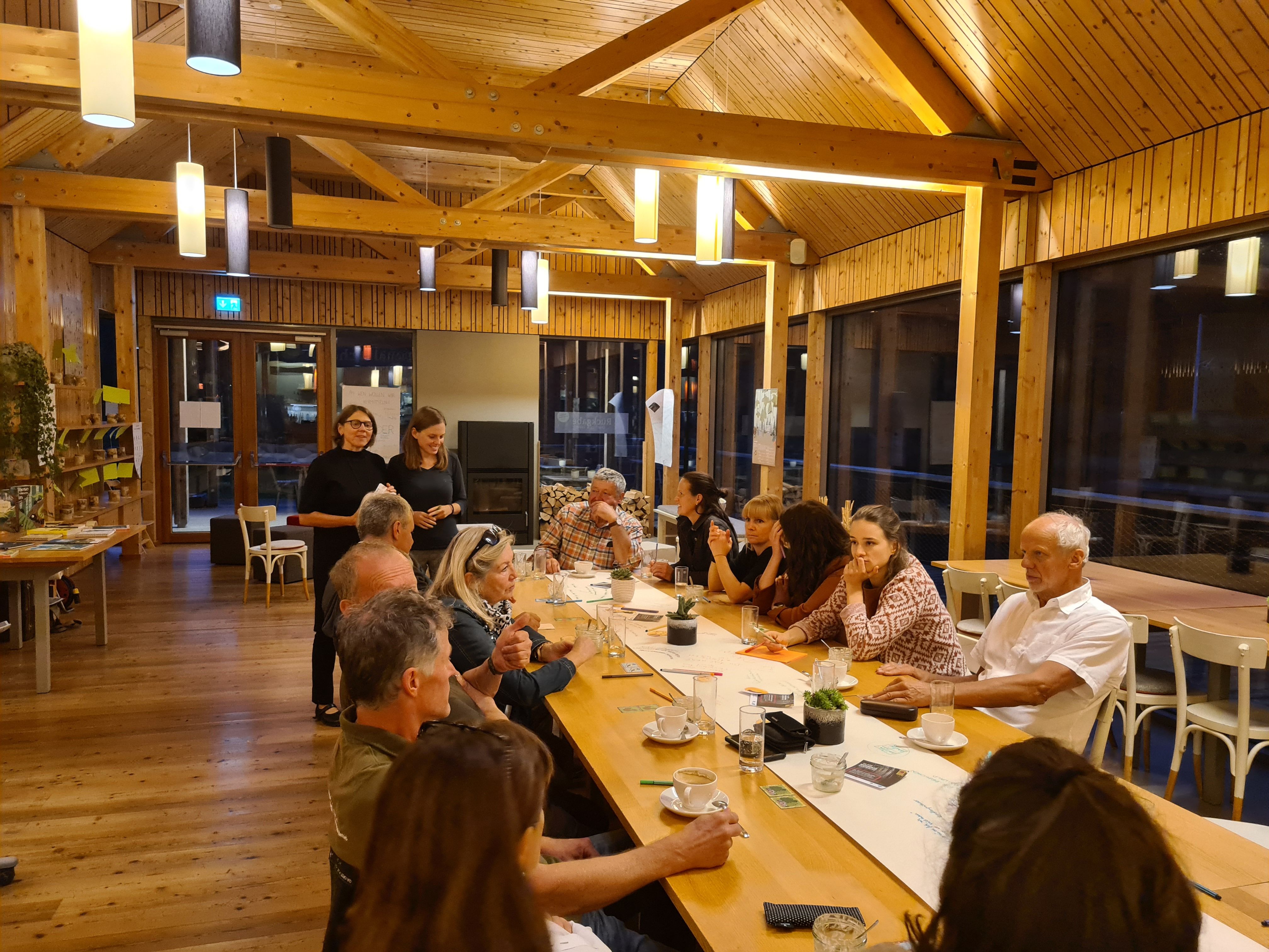 Eine Gruppe von Menschen sitzt rund um einen großen Tisch und unterhält sich.