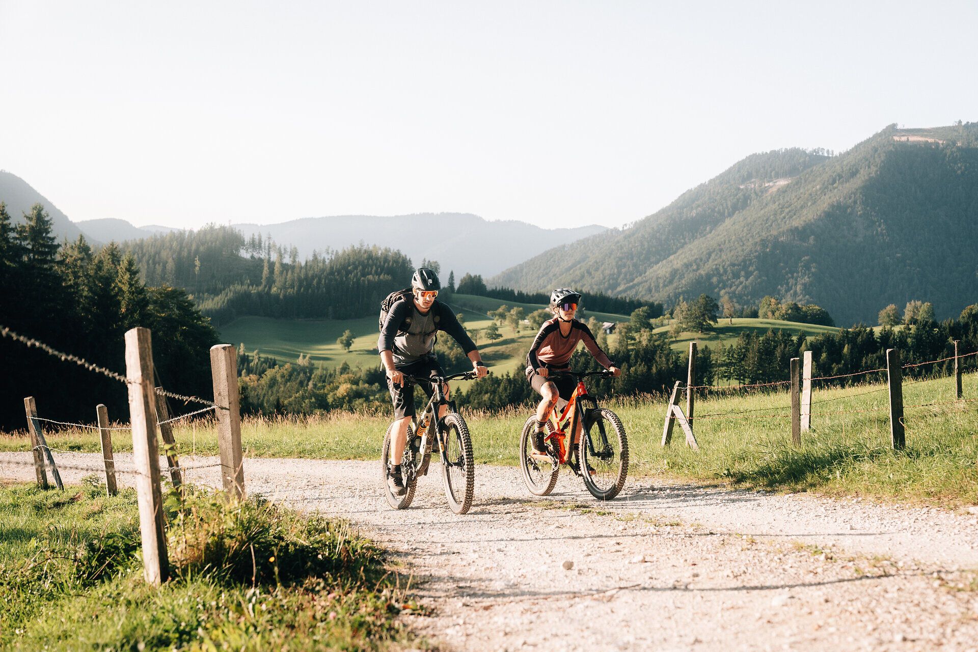 Zwei Mountainbiker genießen die frische Bergluft und die atemberaubende Landschaft des Mostviertels. Umgeben von sanften Hügeln und üppigem Grün, strahlt die Szenerie eine einladende Ruhe aus, die zum Entdecken einlädt.