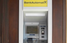 Ein Bankautomat mit gelbem Schild und Raiffeisen-Logo.