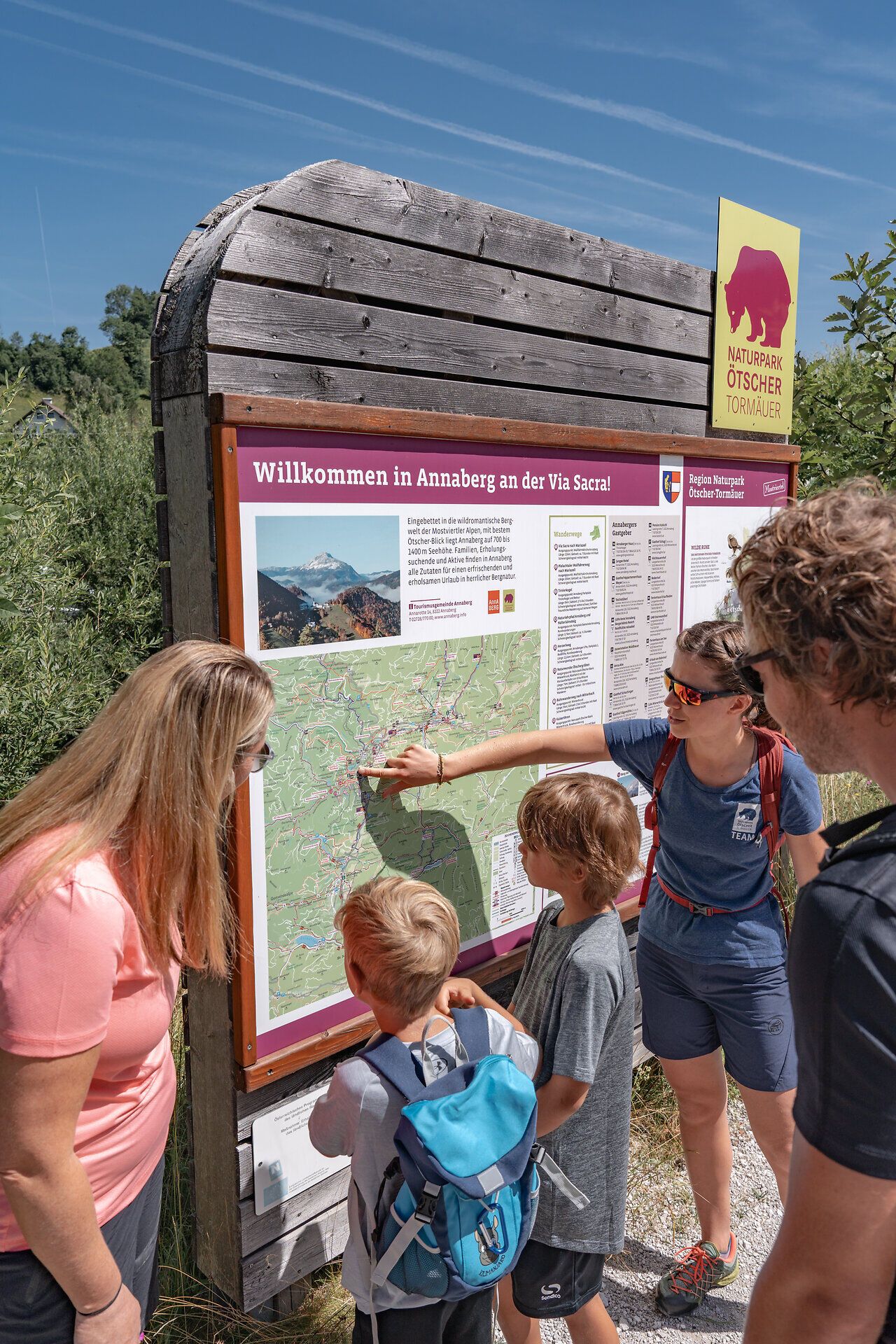 Familien genießen einen spannenden Moment, während sie die Wanderkarte studieren und sich auf das Abenteuer in der atemberaubenden Natur vorbereiten. Umgeben von üppigem Grün und majestätischen Bergen, verspricht dieser Ort unvergessliche Erlebnisse für Groß und Klein.
