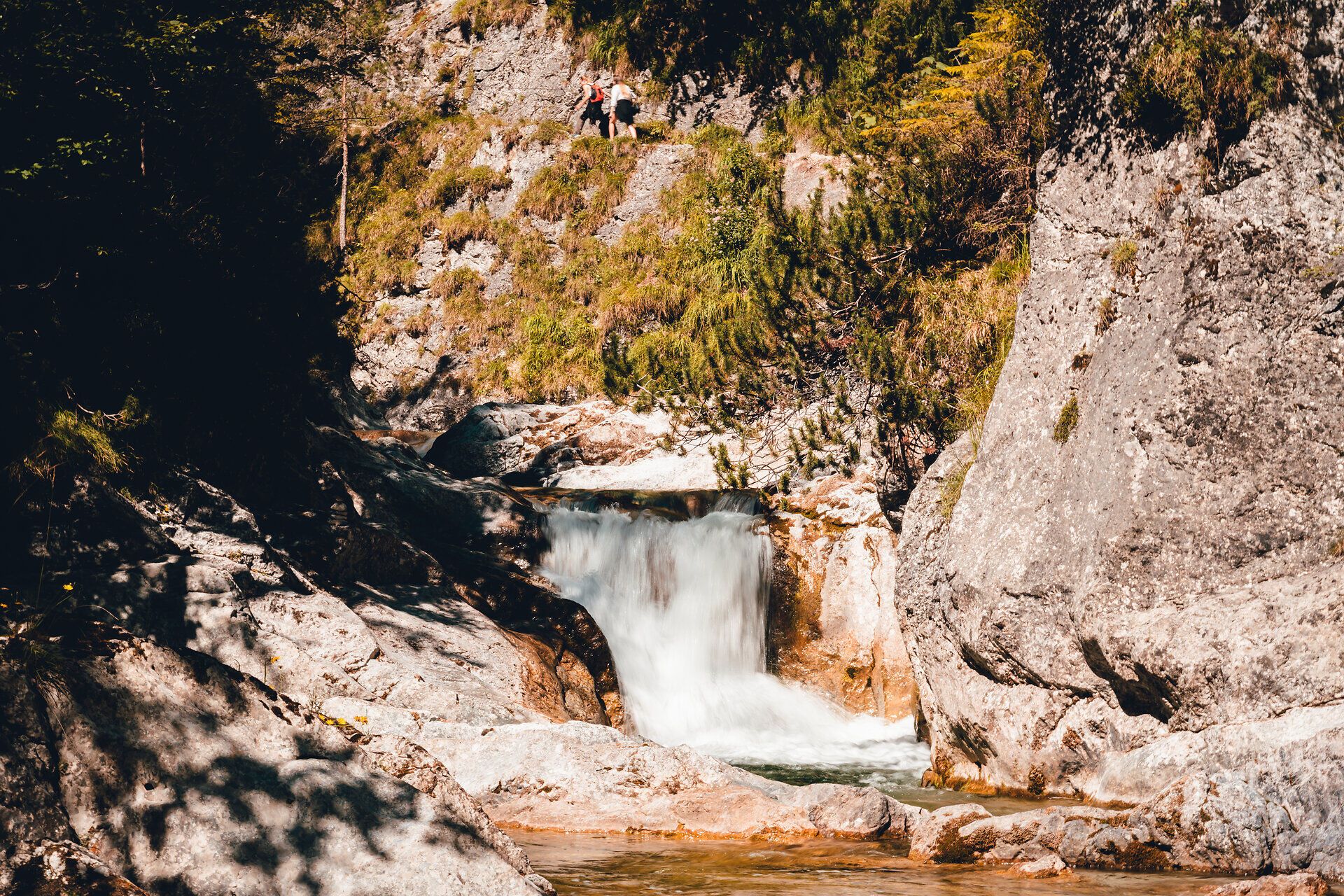 Ein sanft plätschernder Wasserfall umrahmt von majestätischen Felsen und üppigem Grün lädt zu einer erfrischenden Auszeit in der Natur ein. Die klare Luft und das beruhigende Geräusch des Wassers schaffen eine harmonische Atmosphäre, die Wanderer und Naturliebhaber gleichermaßen begeistert.