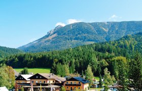 Blick auf ein Campinggelände mit Gebäuden vor einem bewaldeten Bergmassiv.