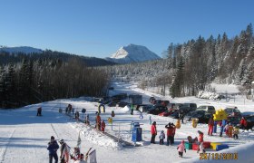 Winterlandschaft mit Skilift und spielenden Kindern in Puchenstuben.