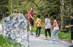 Eine Kindergruppe wird am Seil über den Bauernhof geführt.