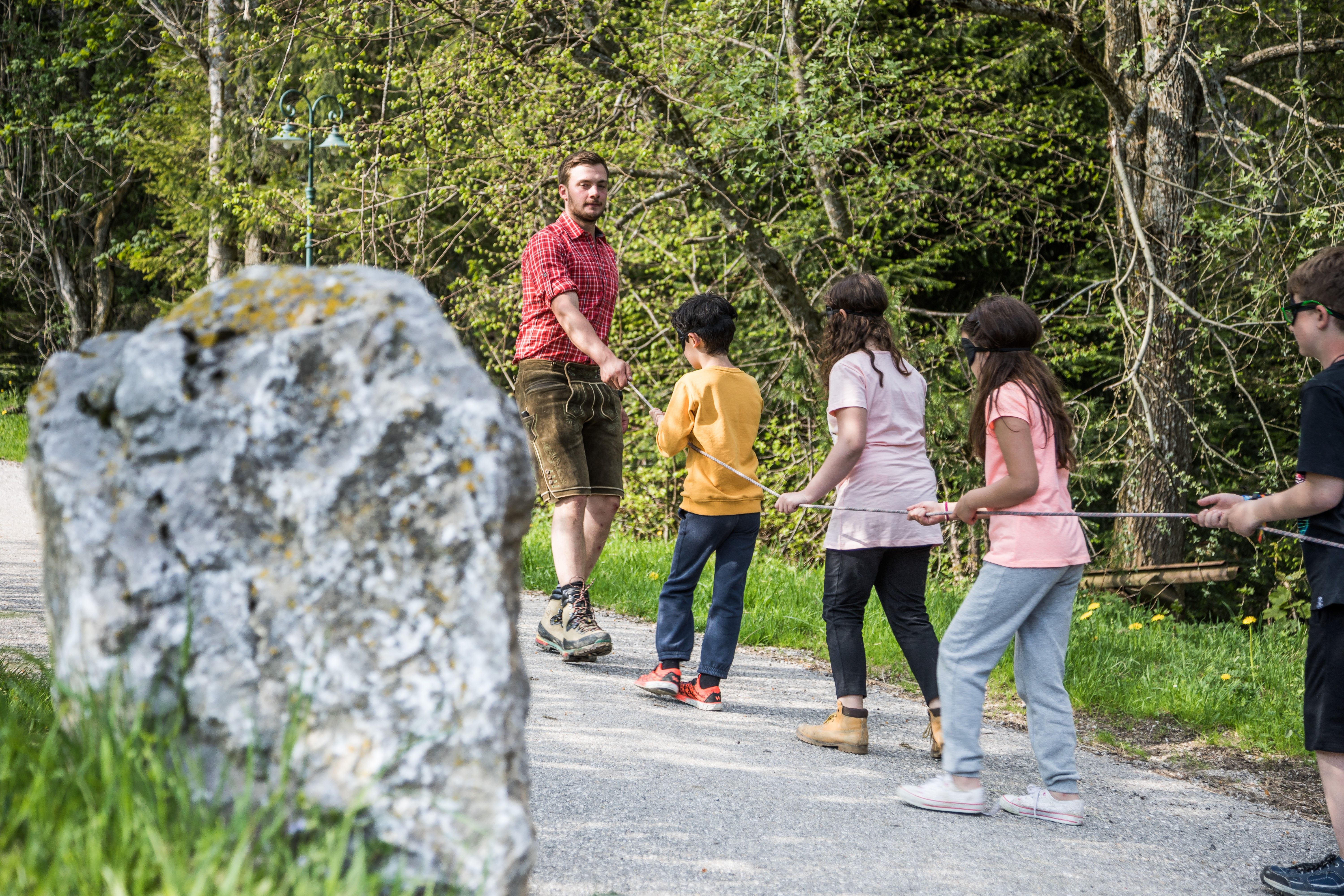 Eine Kindergruppe wird am Seil über den Bauernhof geführt.