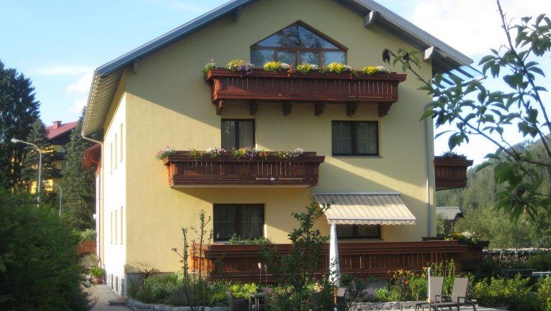 Haus Friedenstein, © zVg Haus Friedenstein Gelbes Haus mit Holzbalkonen und Garten.