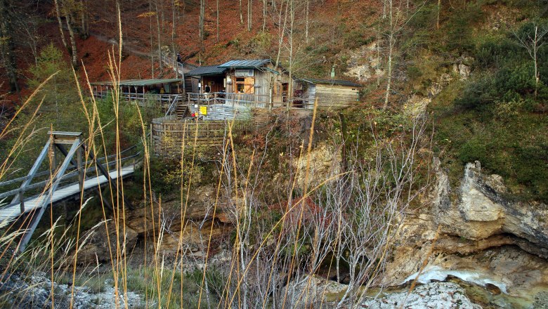 Holzhütte in den Ötschergräben mit Brücke und herbstlicher Landschaft.