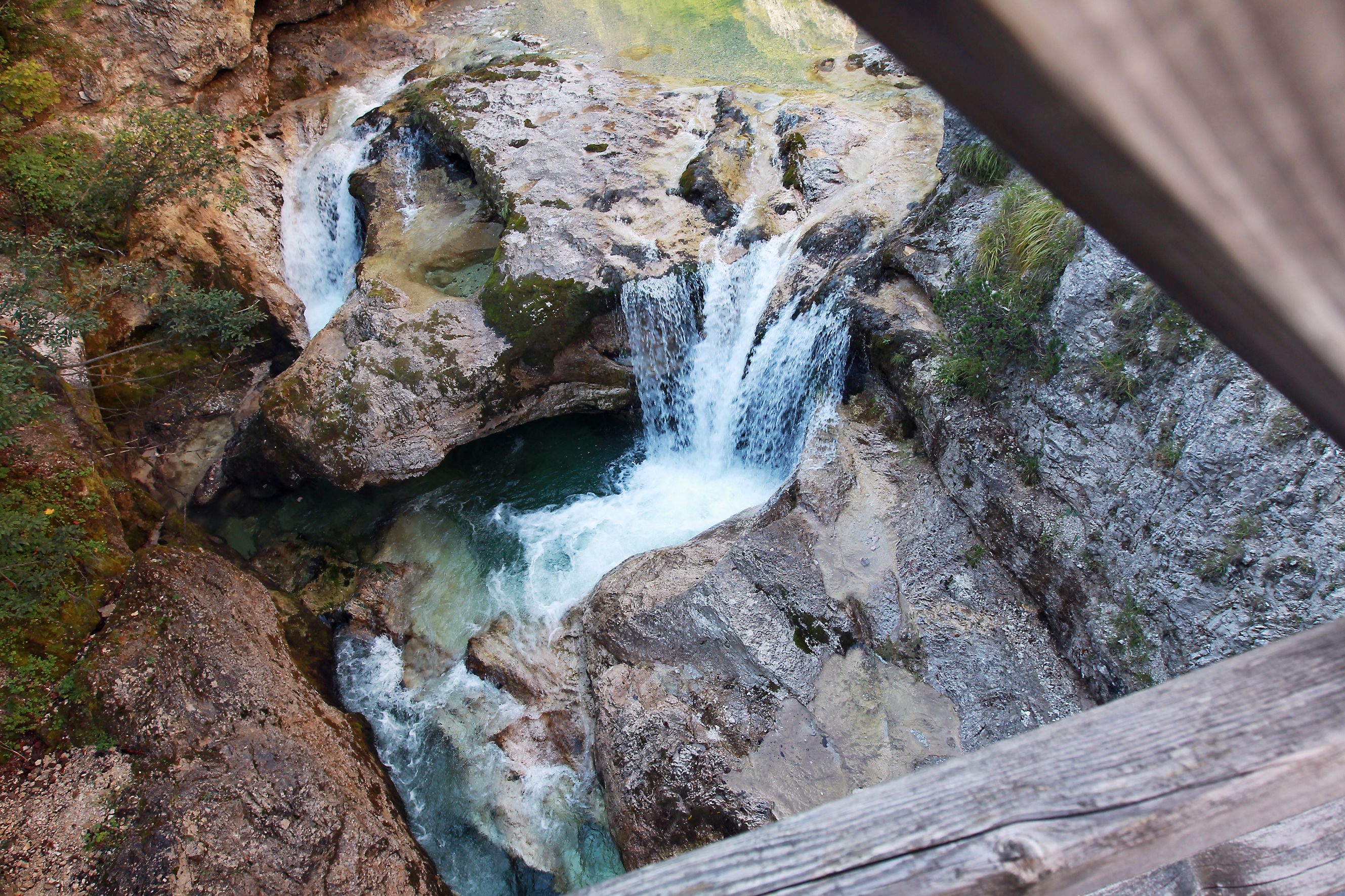 Blick von oben auf einen Wasserfall in einer felsigen Schlucht.