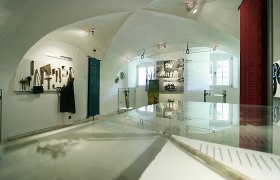 Innenansicht eines Museums mit Werkzeugen und historischen Fotos.