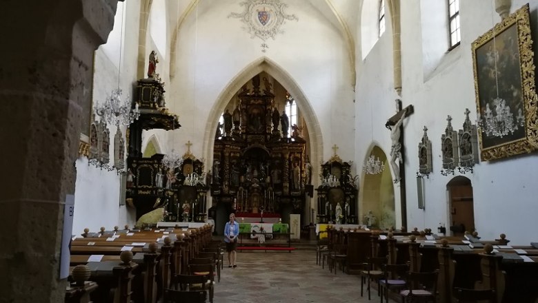 Innenansicht einer Wallfahrtskirche mit Altar, Bänken und religiösen Kunstwerken.