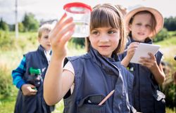 mehrere Kinder blicken gespannt in eine Becherlupe