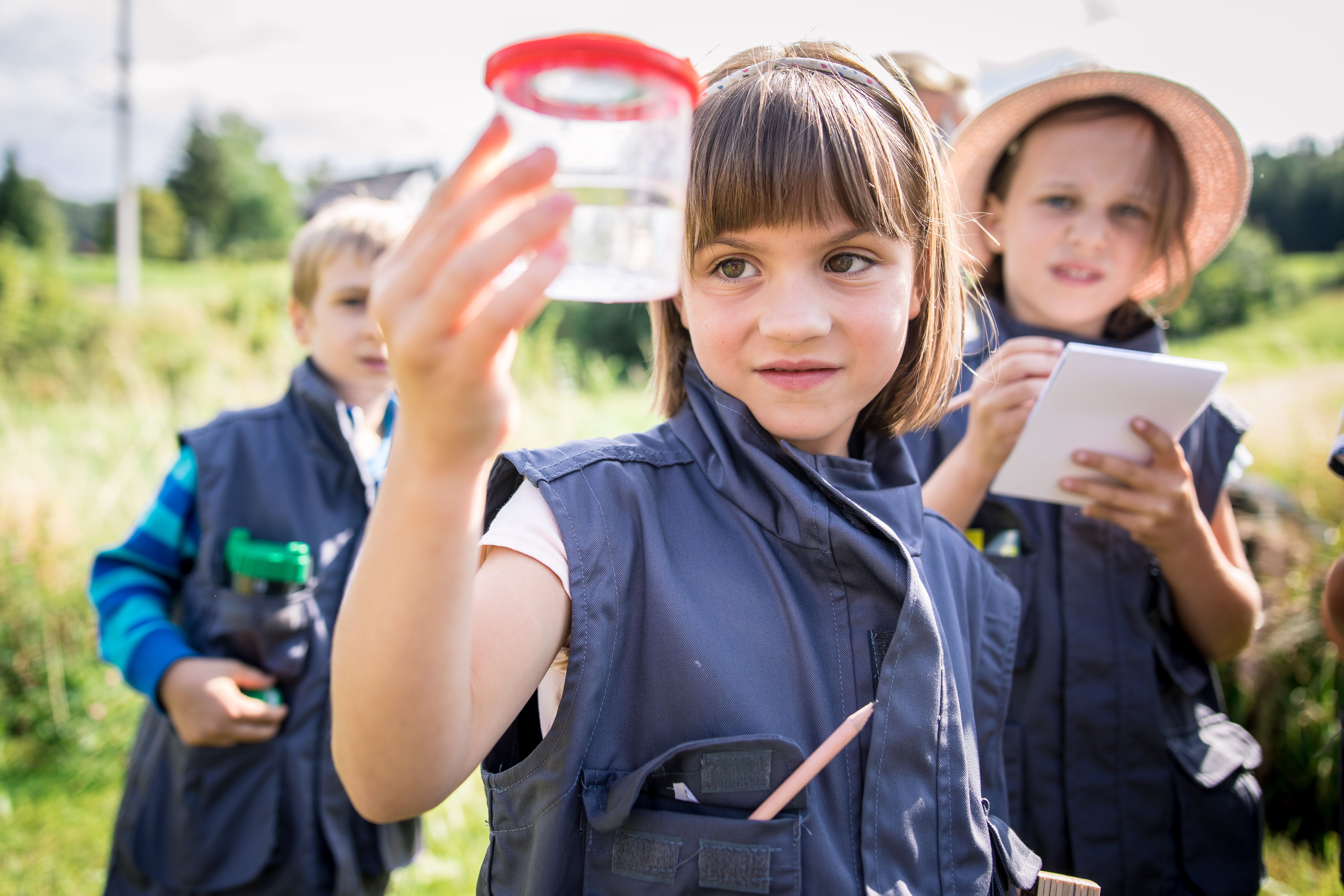 mehrere Kinder blicken gespannt in eine Becherlupe